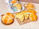 Various bread-shaped products on a wooden board and beige surface
