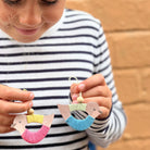 Child holding colorful wooden toys shaped like birds against a wooden background