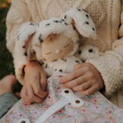 Child holding a soft toy with floral patterned bag