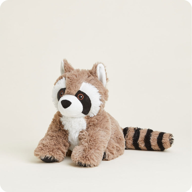 A studio product photo of a plush Raccoon by Warmies sitting upright against a plain background, featuring brown and white fur, distinctive black eye patches, and a striped tail.