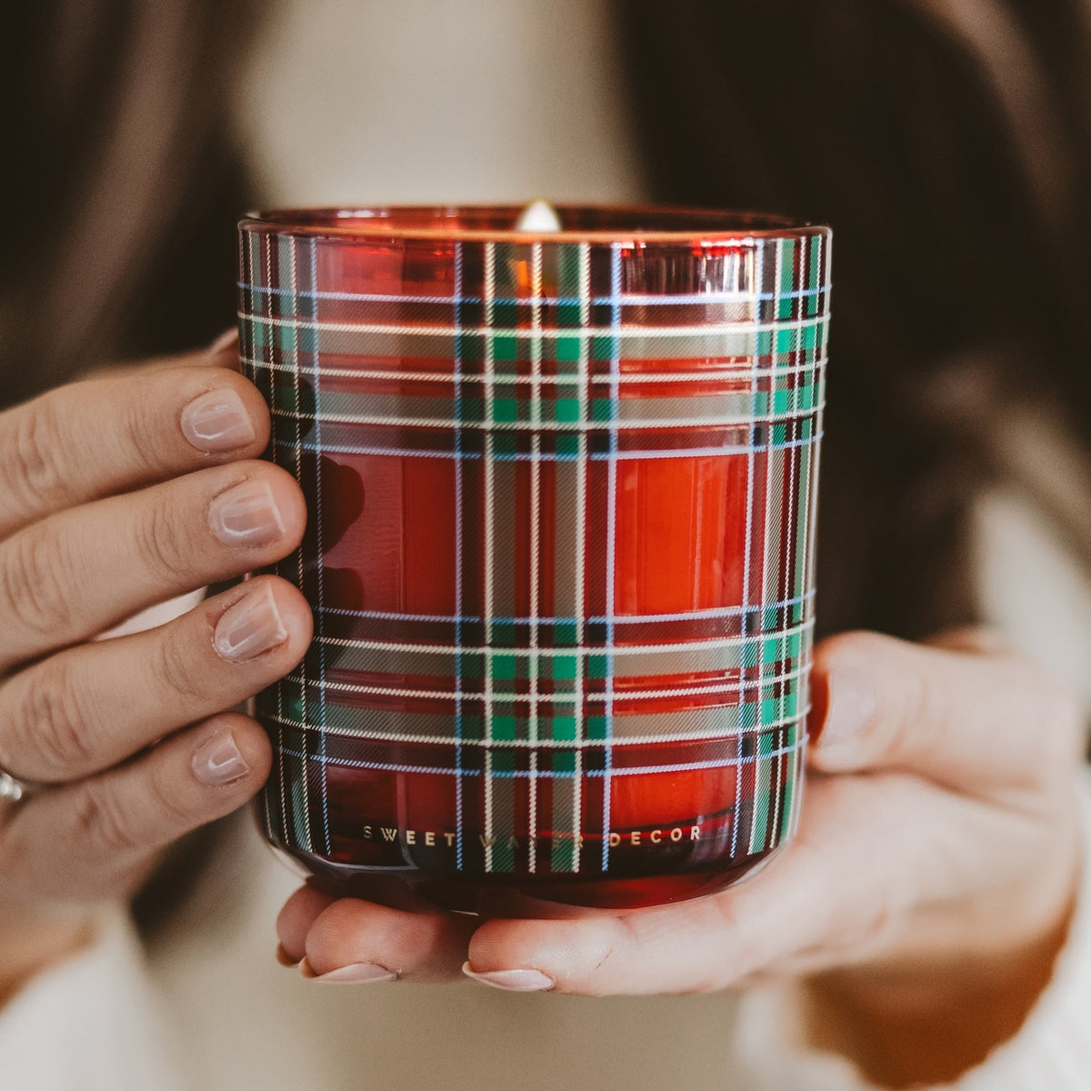 Hand holding a plaid-patterned candle with 'Sweet Decor' branding.