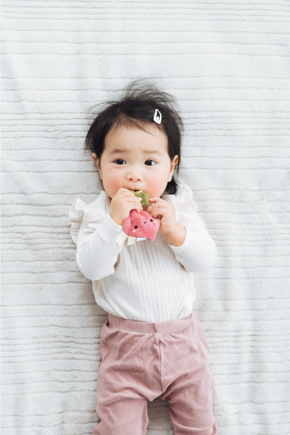 Child holding a pink toy against a textured white background