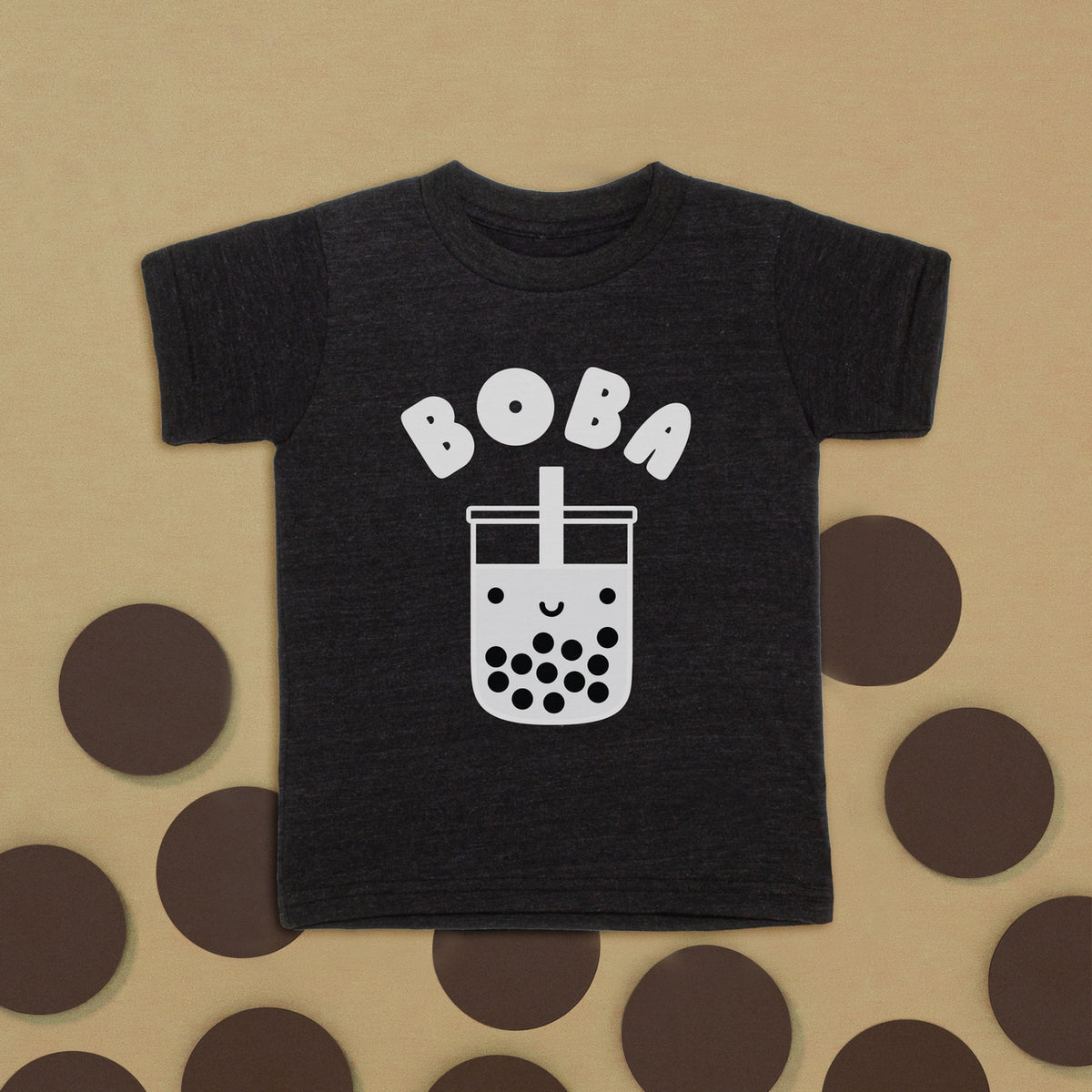 Black t-shirt with 'BOBA' and bubble tea graphic on a beige background with brown circles.