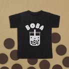 Black t-shirt with 'BOBA' and bubble tea graphic on a beige background with brown circles.