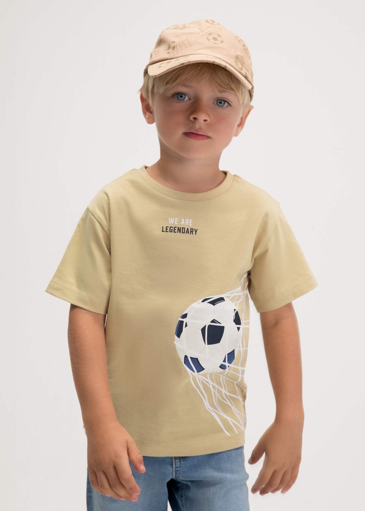 Child wearing a beige t-shirt with a graphic design on a plain background