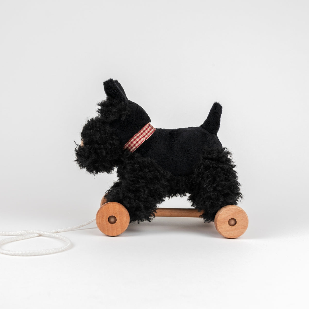 Black dog-shaped pull toy with wooden wheels on a white background