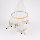 A hanging mobile with a natural wood hoop and four fabric swan figures suspended by white strings against a plain white background.