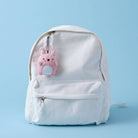 White backpack with a pink bunny charm on a light blue background
