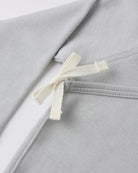 Close-up of a gray garment with a white ribbon tie on a light gray background