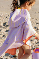 Child wrapped in a striped towel on a beach