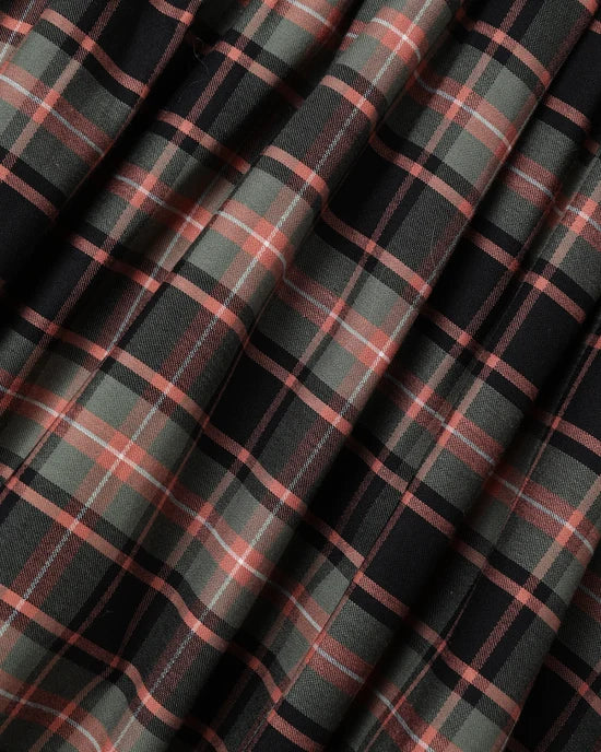 A close-up of draped fabric with a classic plaid pattern in black, muted olive green, and dusty rose pink.