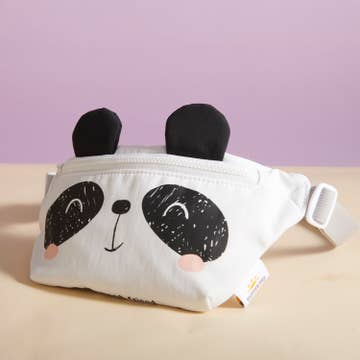 White fanny pack with panda design on a beige surface and purple background