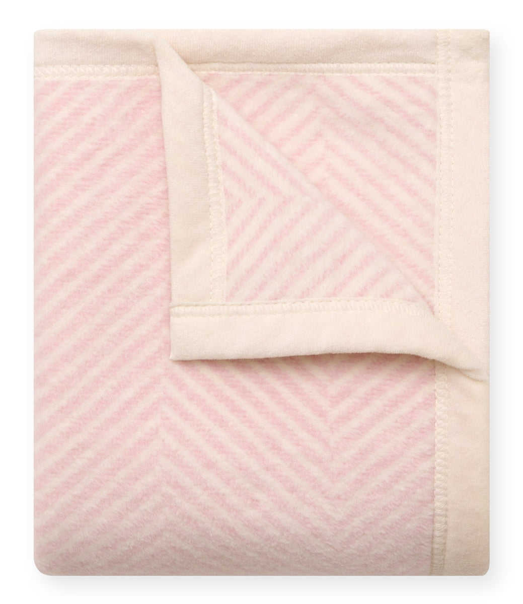 Folded pink and cream chevron pattern blanket on a white background