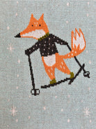Cross-stitched design of a fox skiing on a textured fabric background