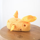 Plush toy resembling a cartoon character on a wooden surface with a white background