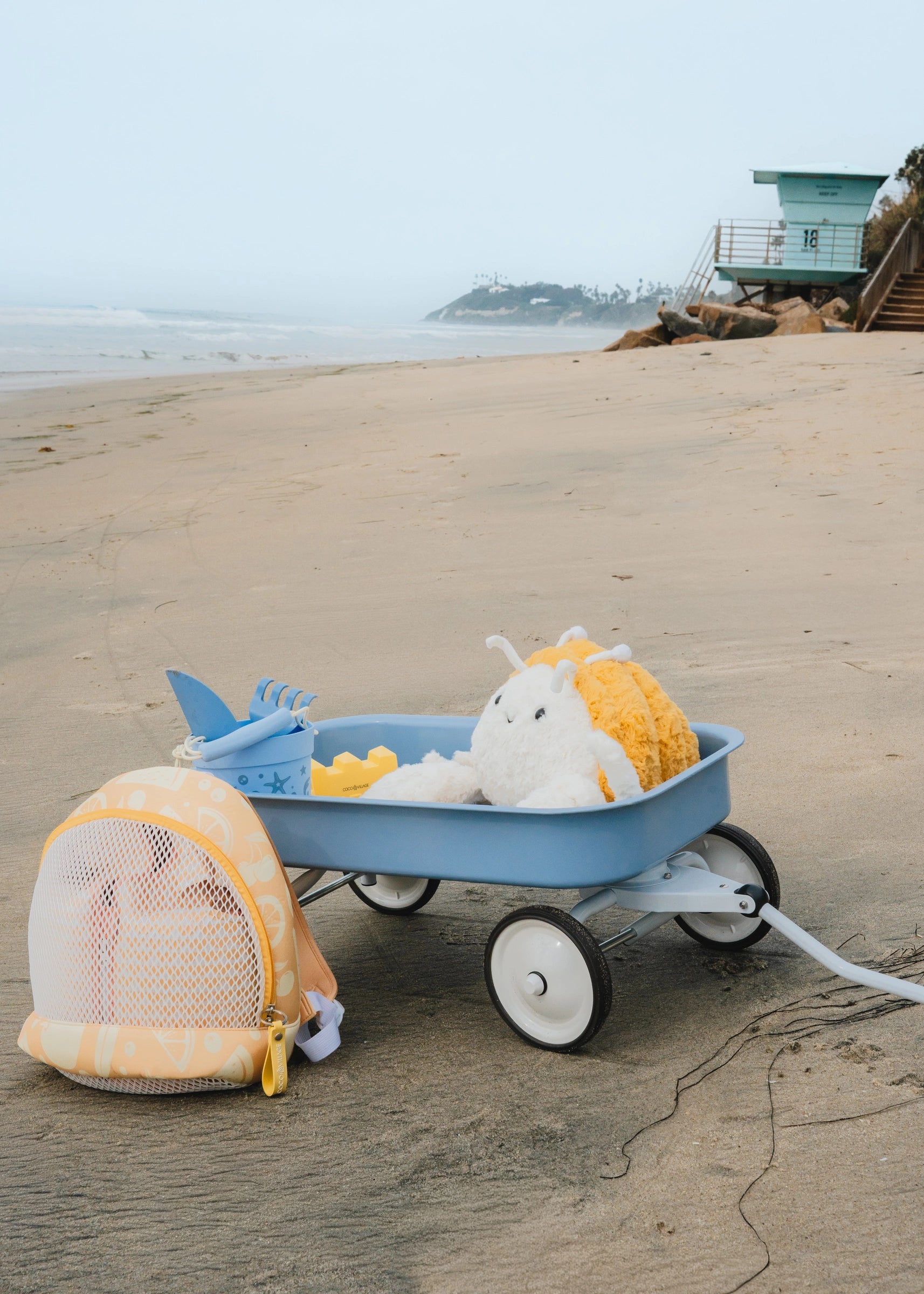 Blue toy wagon with beach items on a sandy beach