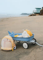 Blue toy wagon with beach items on a sandy beach