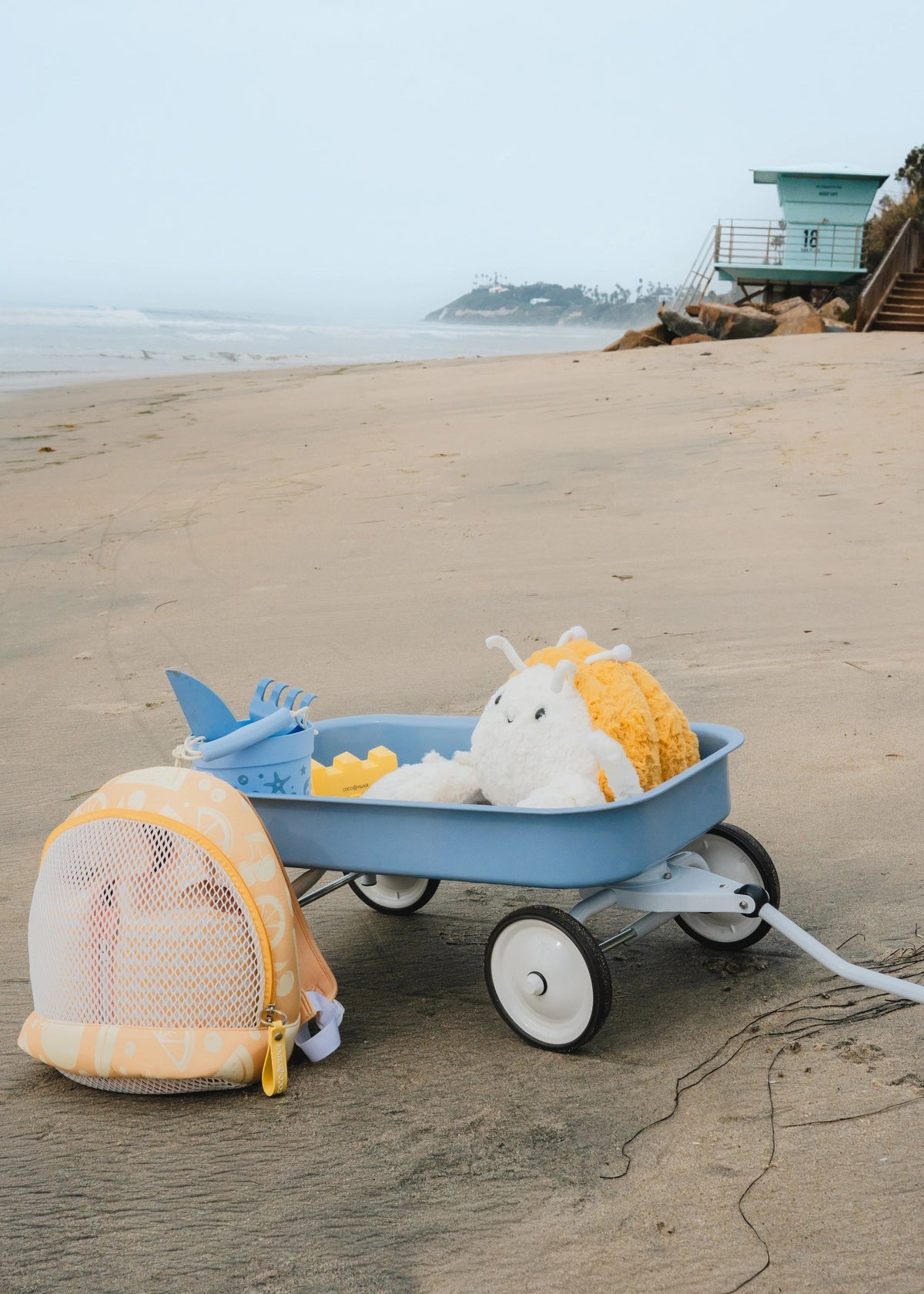 Blue toy wagon with beach items on a sandy beach