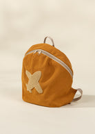 Yellow corduroy backpack with a butterfly patch on a beige background