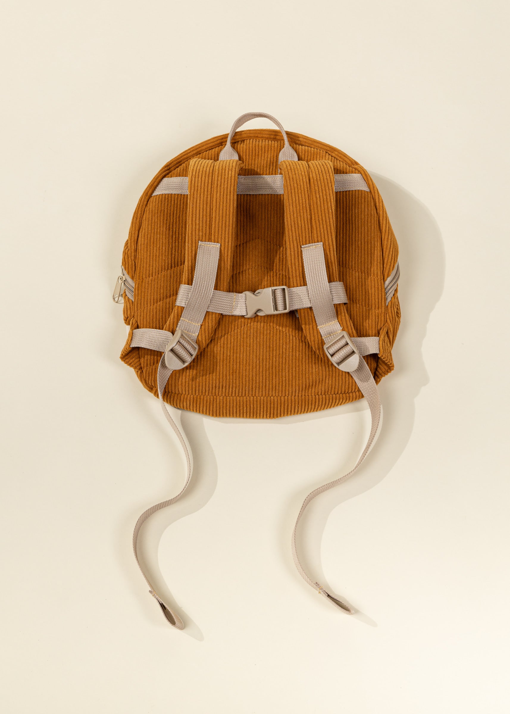 Orange backpack with white straps on a beige background