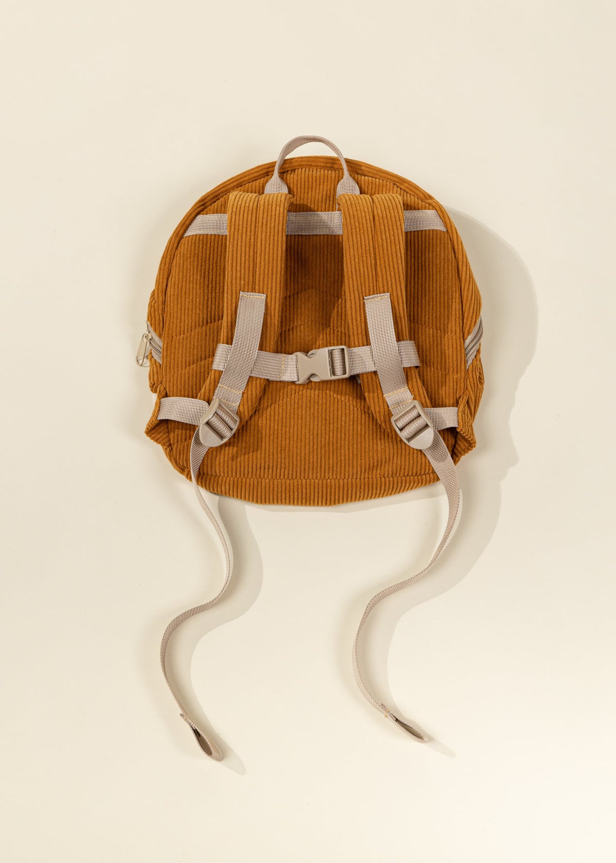 Orange backpack with white straps on a beige background
