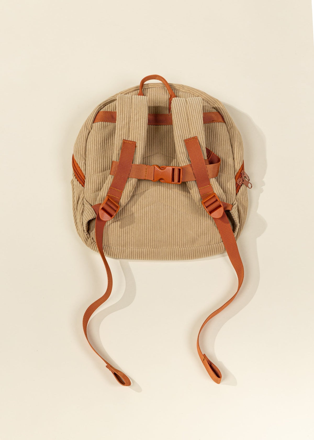 Beige backpack with brown straps on a light beige background