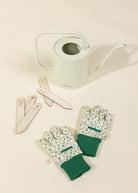 Gardening tools including gloves, labels, and a watering can on a light background