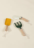 Set of three gardening tools with wooden handles on a beige background