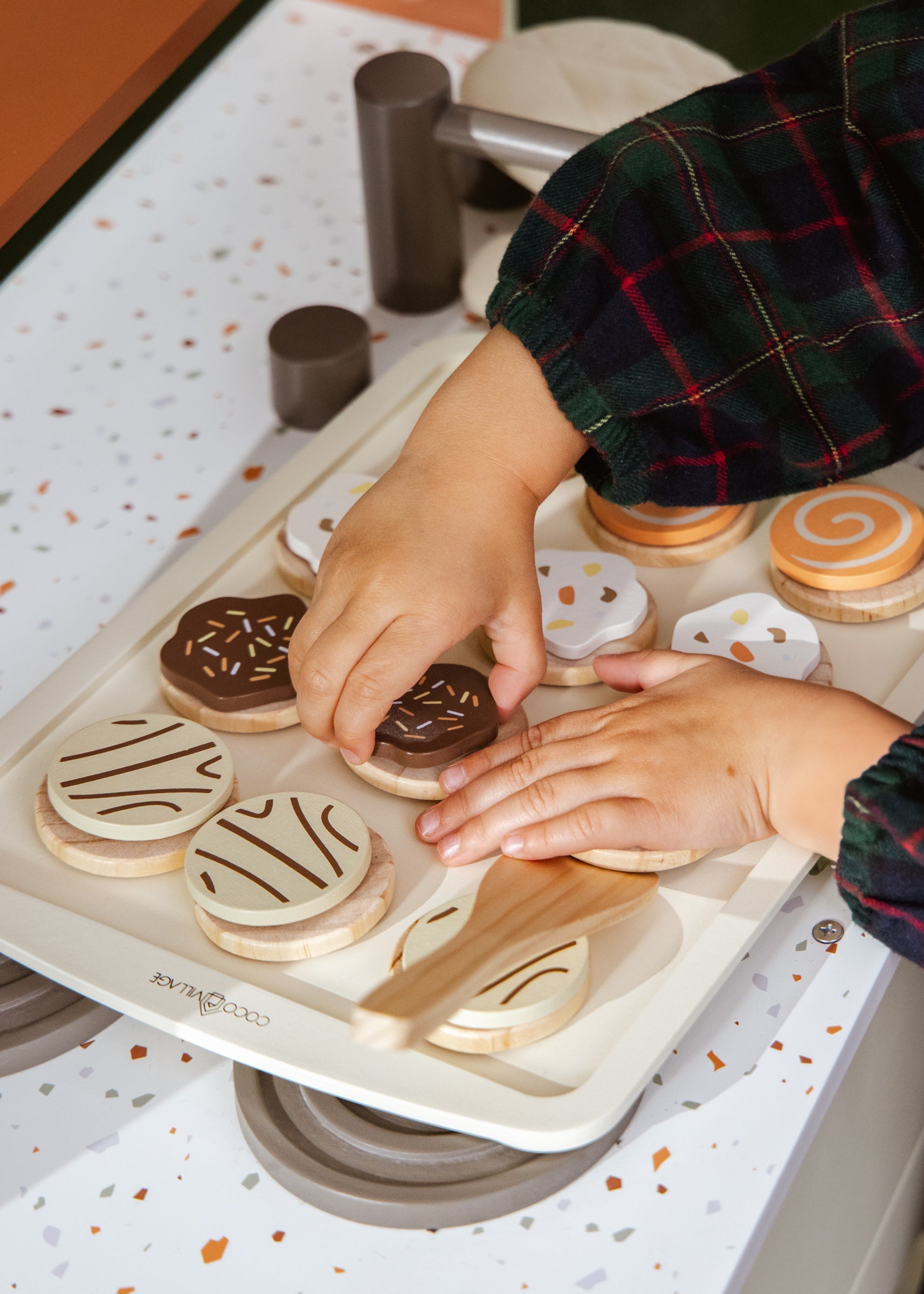 Hands decorating cookies on a baking tray with various cookie cutters.