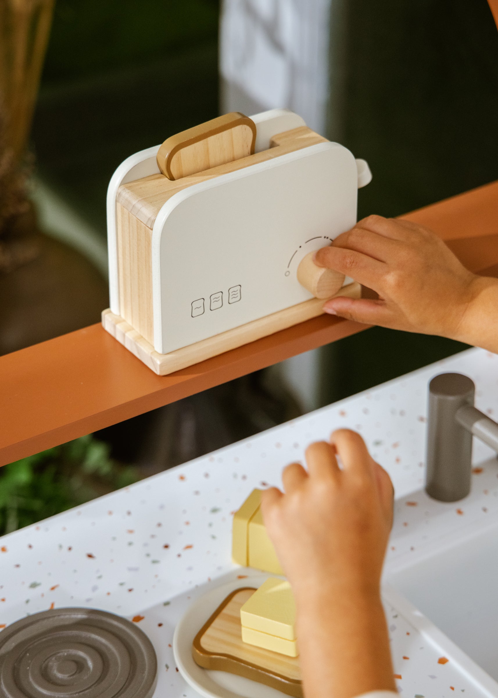 Person using a white toaster with wooden accents on a kitchen counter.