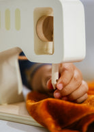Child's hand holding a wooden toy with a white handle