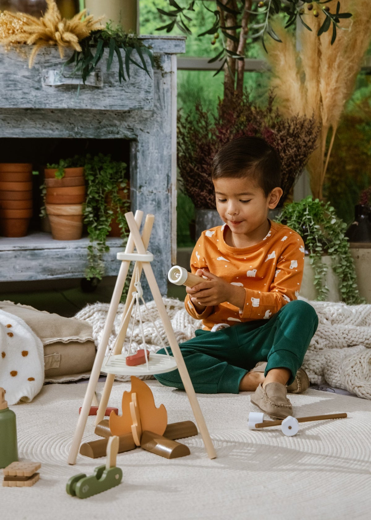 Child playing with wooden toys in a cozy indoor setting with plants and a fireplace.