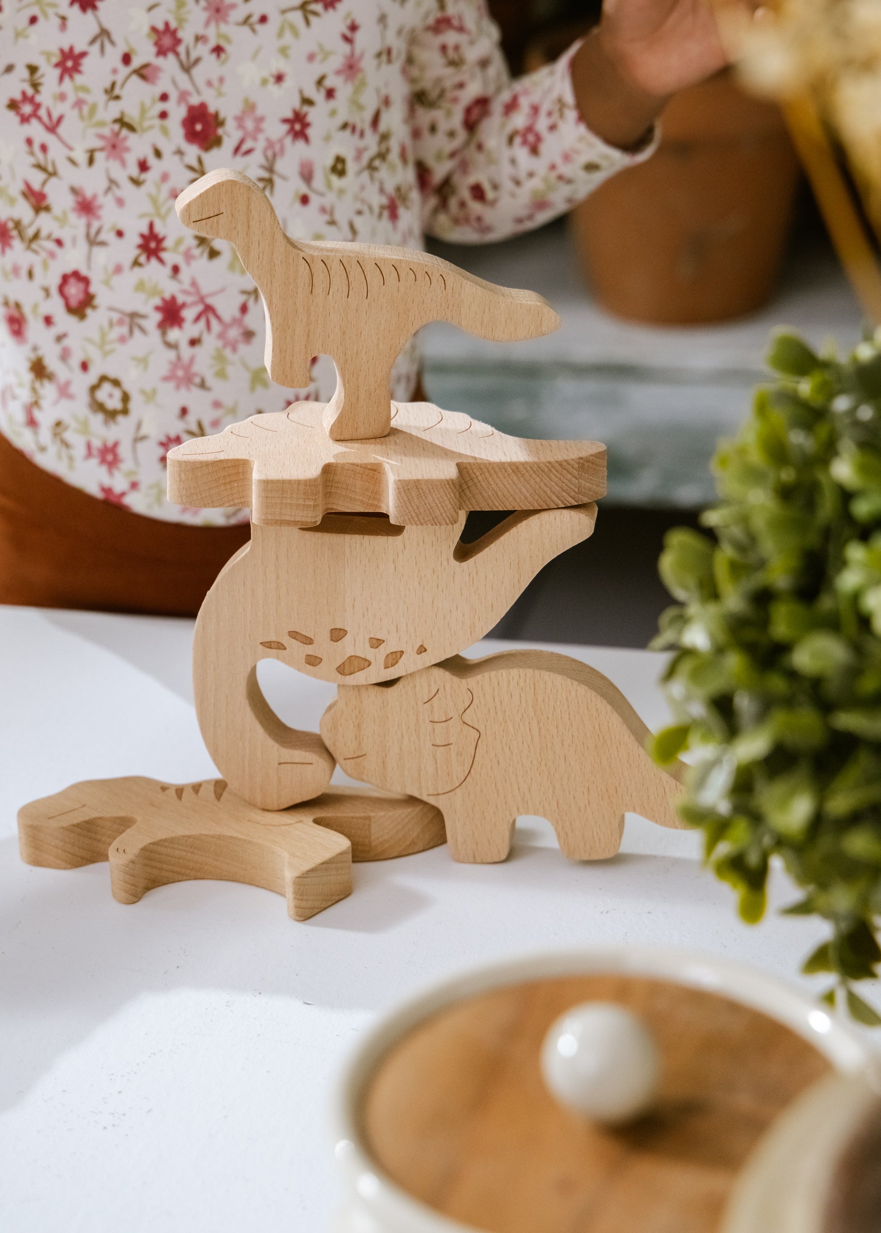 Wooden dinosaur toys on a white surface with a blurred background