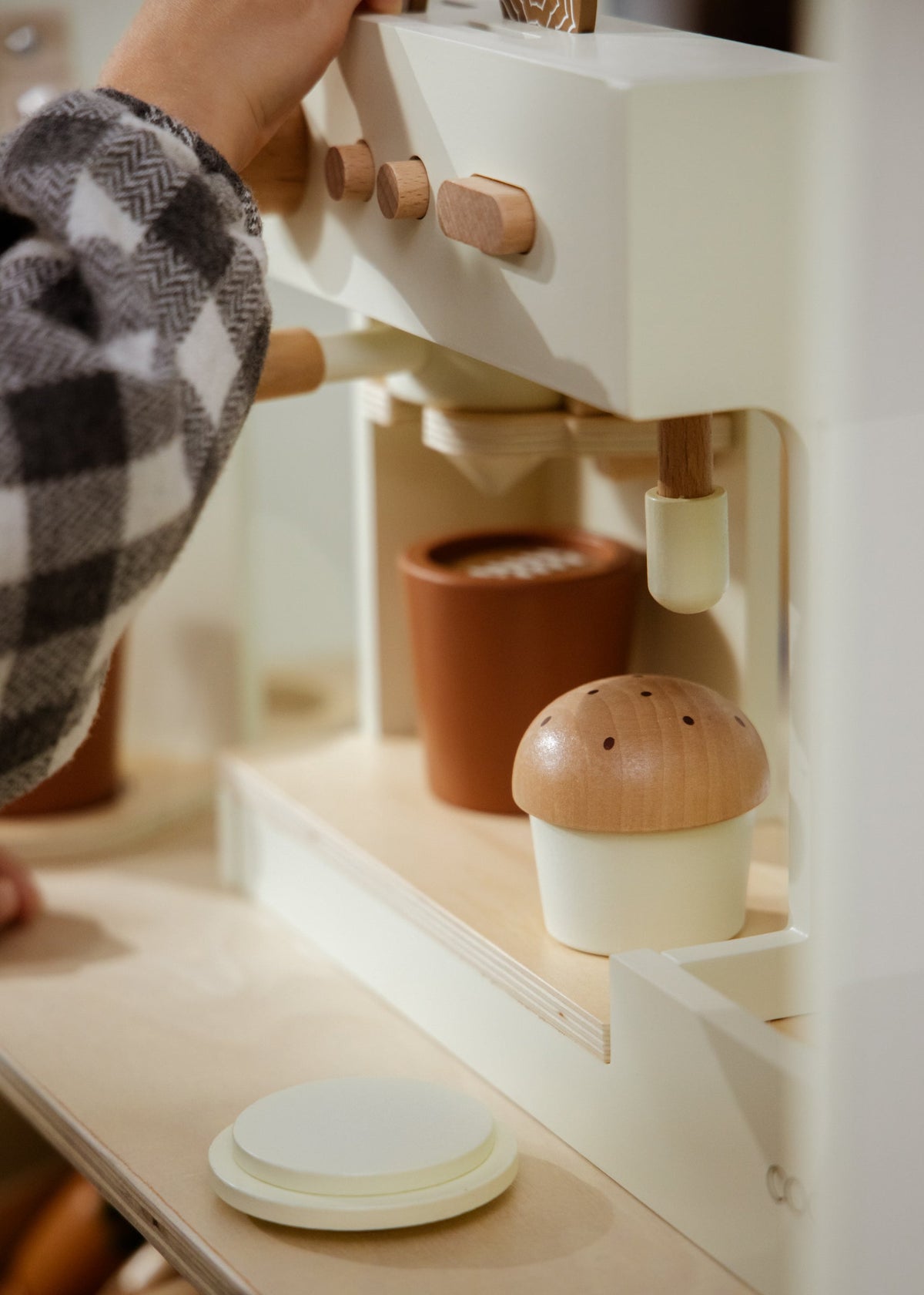 Close-up of a person using a white coffee machine with wooden accents on a wooden surface.