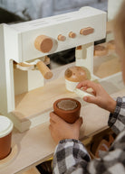 Child playing with a wooden coffee-making set