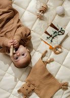 Baby lying on a quilted surface with toys around