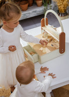 Two children playing with a wooden toy kitchen set on a table.