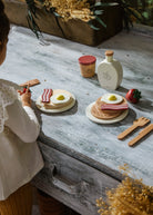 Child playing with toy food and utensils on a wooden surface