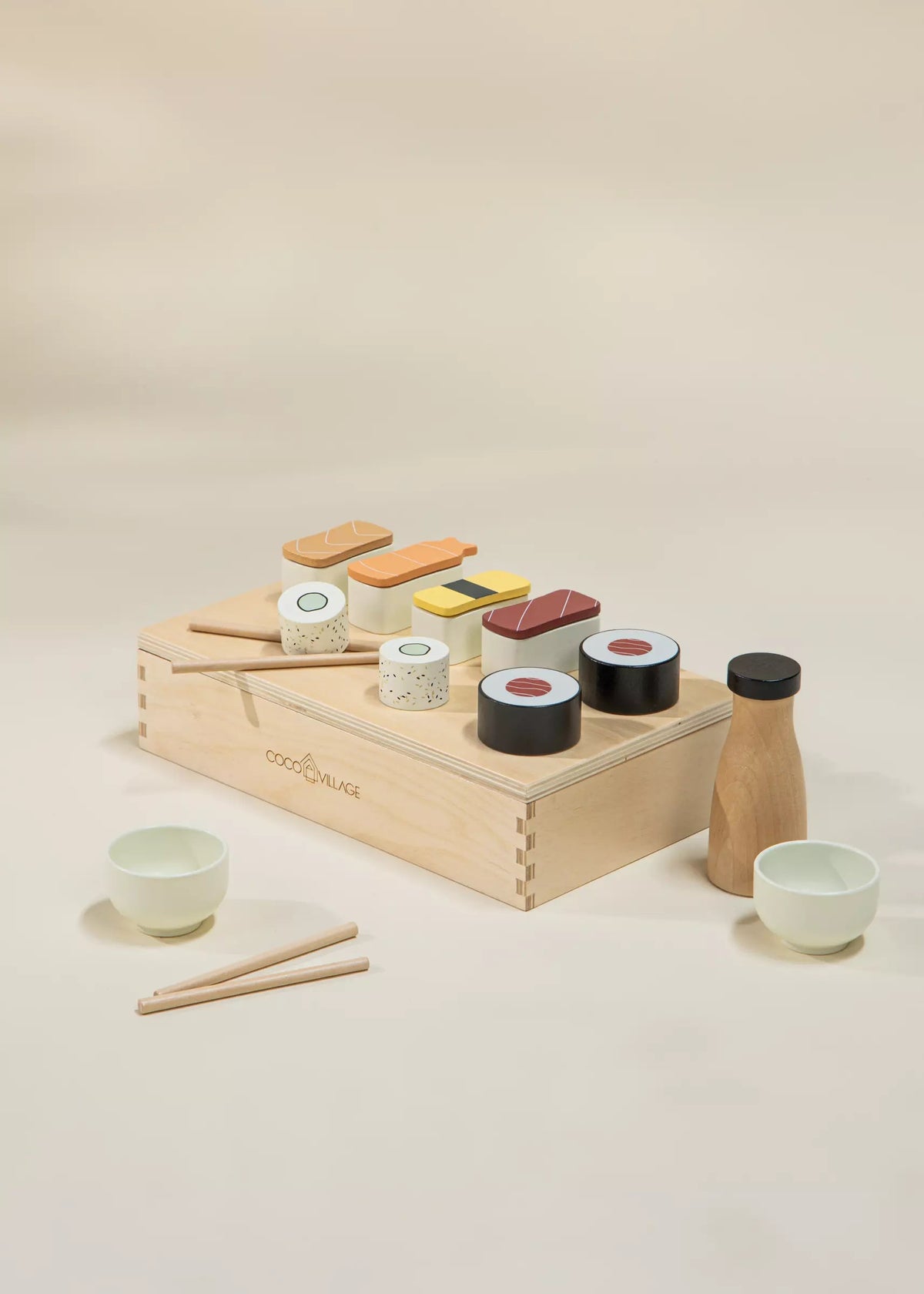 Wooden toy sushi set with various pieces and utensils on a beige background