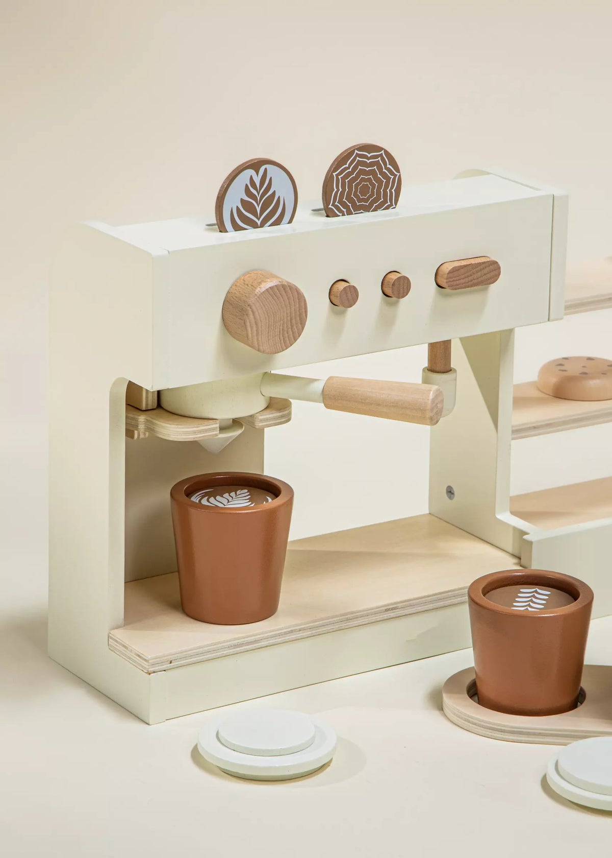 Wooden play kitchen set with pots and pans on a light beige background