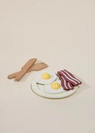 Model of eggs, bacon, and wooden utensils on a beige background