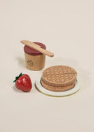 Wooden toy set with a waffle, strawberry, and container on a beige background