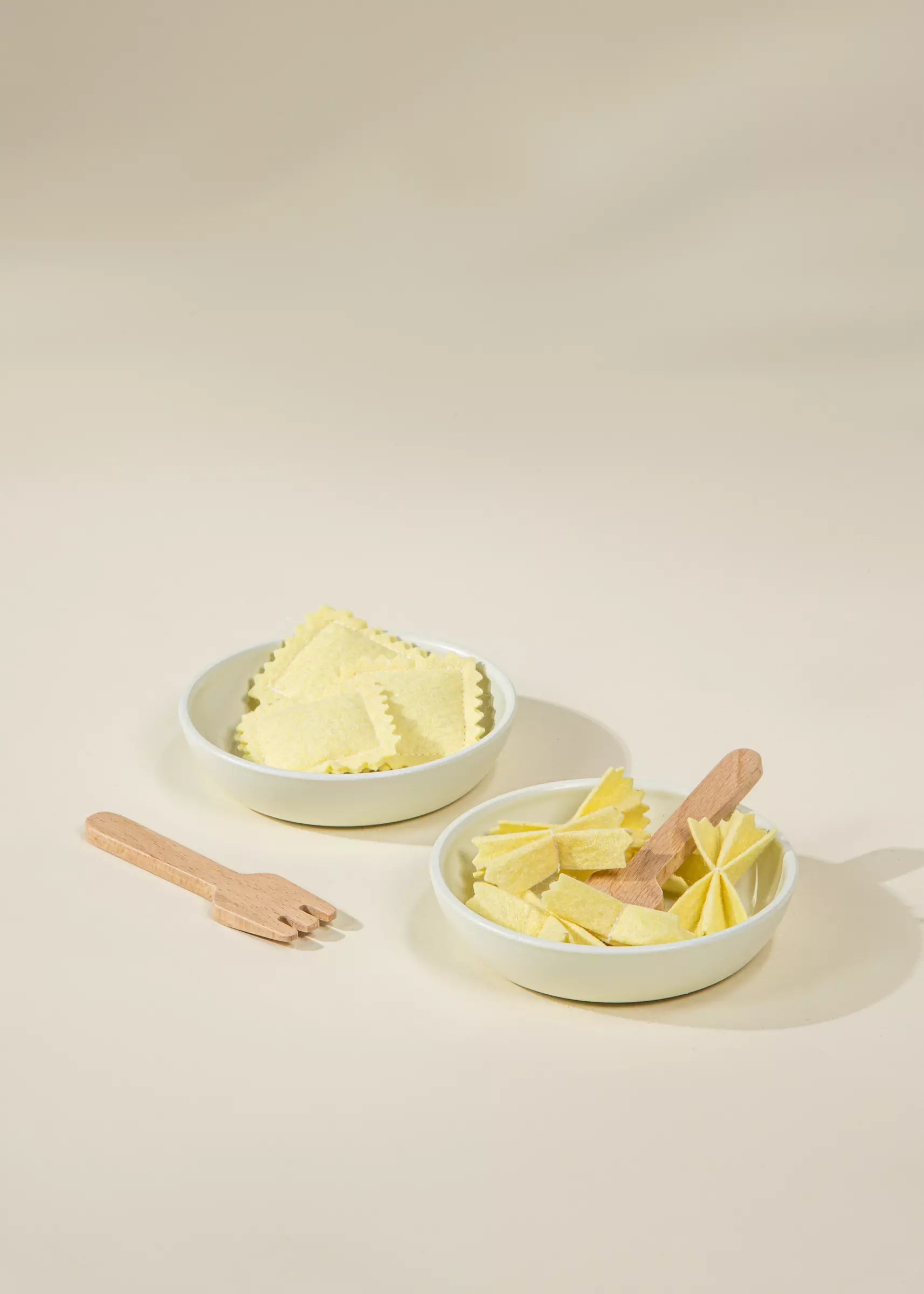 Two white bowls with ravioli on a beige background