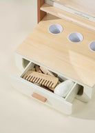 Wooden desk organizer with compartments and a drawer containing office supplies on a light background.