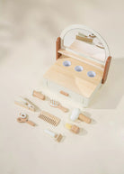 Wooden toy vanity set with mirror and various utensils on a beige background