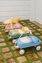 Three toy buggies in pastel colors on a stone and grass surface.