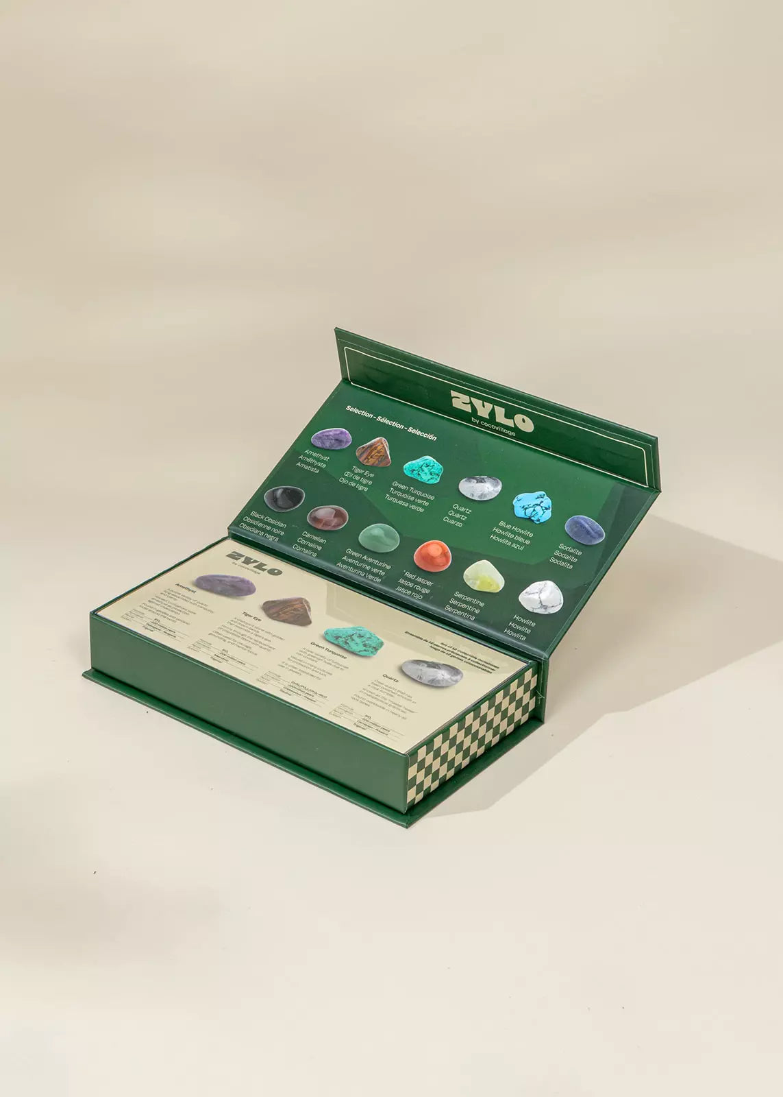 Open green box with gemstones and a ZYLO label on a beige background