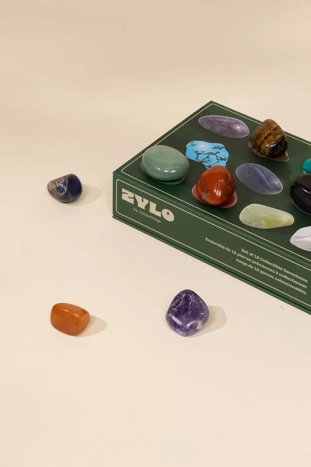 Set of colorful stones in front of a ZYLO branded box on a beige background