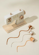 Toy sewing machine with spools of thread on a beige background