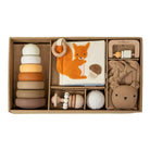 Set of baby toys including wooden rings, plush toy, and book with a fox illustration in a box.